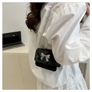Detalle del mini bolso negro de cuero sintético con textura y hebilla de lazo plateado
