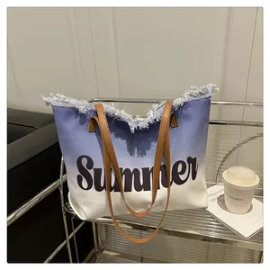 Detail of blue and white gradient canvas tote with fringe trim and Summer text print
