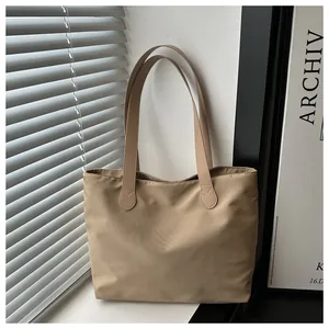 Detail view of khaki nylon tote bag with leather handles on a sunlit windowsill