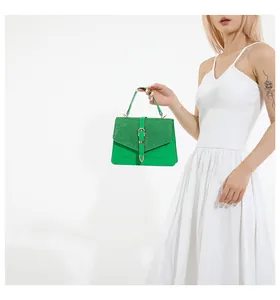 Detail der grünen Lederhandtasche mit Glitzerklappe, gehalten von Model in Weiß