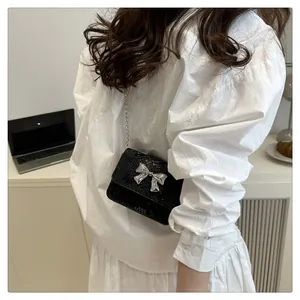Detalle de un mini bolso bandolera negro con lazo plateado y textura de serpiente
