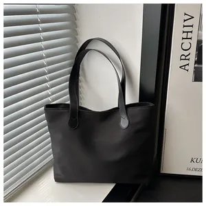 Detail of minimalist black nylon tote bag with reinforced stitching near soft window light