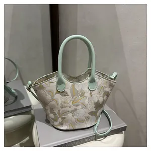 Floral print handbag on props with mint green leather trim and golden metal hooks