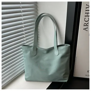 Detail of mint green tote bag showing glossy synthetic fabric and reinforced handle stitching