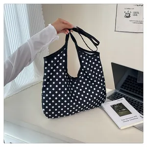 Detailed view of spacious black tote bag with white polka dots and reinforced handle