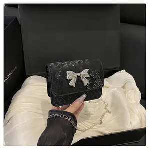 Detalle de mini bolso negro con estampado de serpiente y hebilla de lazo plateada