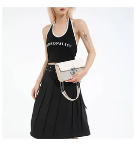 Detail of cream white crossbody bag with metal ring buckle and chain strap on model