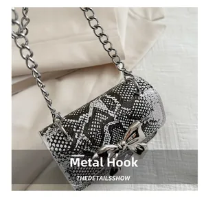 Detail shot of silver metal hook and sleek snakeskin texture on a mini crossbody bag