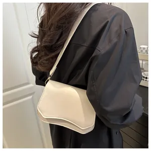 Model view of cream asymmetrical leather crossbody bag with gold hardware and shoulder strap