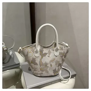 Detail of floral embroidery on a minimalist cream crossbody bag with leather strap