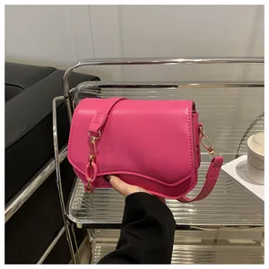 Detail of fuchsia square bag featuring a curved flap, pink chain link, and gold buckle