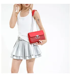 Detail of red sequined shoulder bag with silver metal buckle and chain strap on model