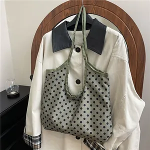 Large green polka dot tote bag for women shown hanging in a minimalist home setting