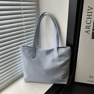 Minimalist light blue tote bag with long straps on a windowsill in soft sunlight