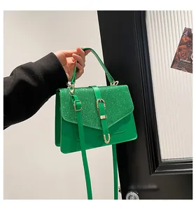 Detail der grünen Handtasche mit Glitzerklappe, goldener Schnalle und Riemen
