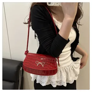 Macro detail of red crocodile texture small flap bag with a golden metal bow accessory