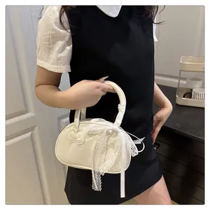 Detail of cream leather handbag featuring cat embossed pattern and white lace bow