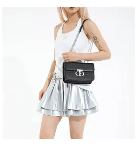 Detail of black sequined flap bag with silver chain strap worn with a metallic skirt