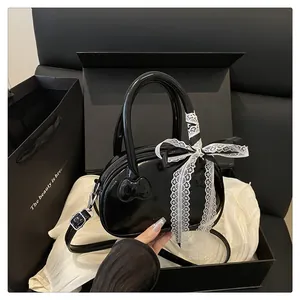 Detail of black patent leather mini bag with 3D kitty embossing and lace bow accessory
