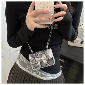Detail view of mini snake pattern crossbody bag with silver bow and chain strap