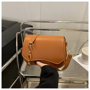 Close-up of caramel brown handbag featuring wavy flap edge and thick chain decoration