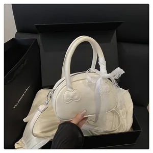 Detail of a cream bowling bag featuring an embossed bow and white lace ribbon decoration