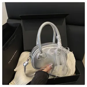 Close-up of metallic silver bowling bag with white lace bow and detachable strap