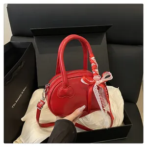 Detail of red heart-shaped patent leather bag with lace bow and silk ribbon handle
