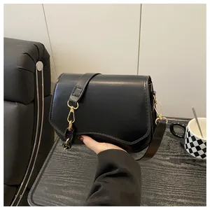 Detail of black leather crossbody bag with wavy base, gold hardware and chain strap