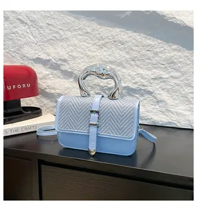 Détail du sac bandoulière bleu clair avec texture tressée et poignée en métal liquide