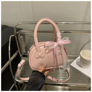 Close-up of pink patent leather handbag with bow relief and decorative lace details