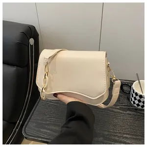 Close-up of beige crossbody bag with golden hardware and acrylic chain link strap
