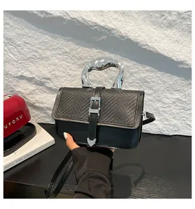 Détail d'un sac à bandoulière noir avec texture tressée et poignée en métal argenté