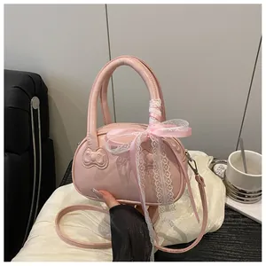 Close-up of pink bow-embossed leather handbag with lace ribbon on a soft white silk fabric