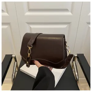 Close-up of a dark brown square handbag with gold hardware and stylish wave-edge bottom