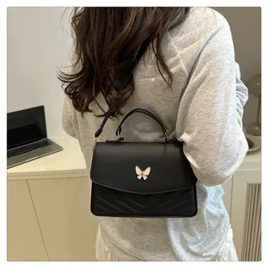 Shoulder bag detail showing black matte PU leather with V-quilt and butterfly clasp