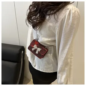 Detail of red snake-pattern mini crossbody bag with silver bow and metal chain strap