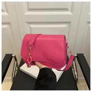 Detail of rose pink handbag with wavy flap design and decorative gold chunky chain