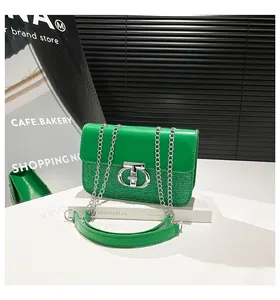 Detail of green sequin handbag featuring a silver chain strap and metal lock closure