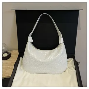 Detail of white woven leather crescent bag with textured pattern and zipper in a gift box