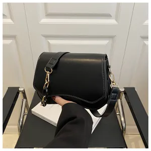 Detail of black faux leather bag with curved bottom and gold chain shoulder strap