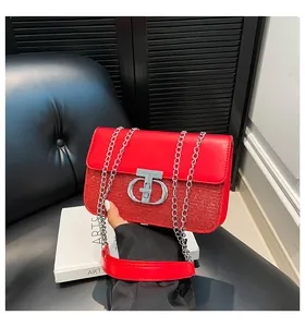 Detail of red glitter shoulder bag with silver CD buckle on a black leather sofa