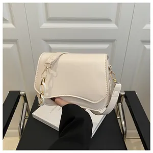 Detail of cream leather shoulder bag with unique wavy flap and chunky gold chain strap