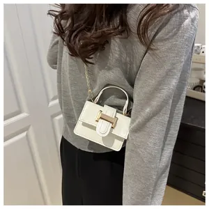 Detail view of mini white crossbody bag with gold H-buckle and metallic chain strap