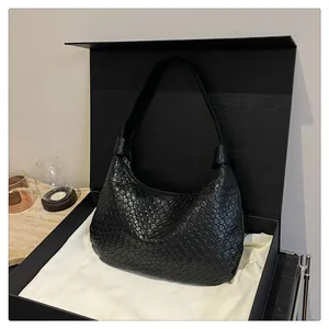 Detail of black woven leather tote bag presented in a luxury gift box with white fabric