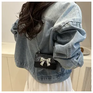 Detailed back view of a black mini crossbody bag with silver bow on denim outfit