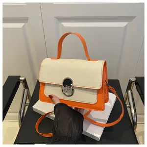 Detail of orange woven crossbody bag with metallic twist lock and top handle strap