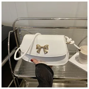 Gros plan détaillé d'un sac à main blanc orné d'une boucle en nœud papillon doré