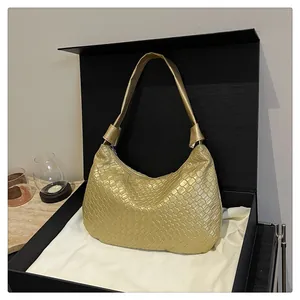 Detailed shot of gold woven texture hobo bag with knotted strap in a premium gift box