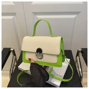 Detail of green leather and canvas crossbody bag featuring a golden oval metal lock